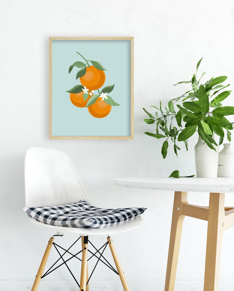 Pode incluir: Uma impress&atilde;o emoldurada de uma ilustra&ccedil;&atilde;o estilizada de tr&ecirc;s laranjas em um galho com folhas verdes e flores brancas sobre um fundo azul claro.