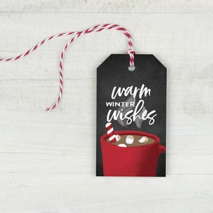 May include: A black gift tag with the words "warm winter wishes" in white script. A red mug of hot chocolate with marshmallows and a candy cane is illustrated below the text. A red and white string is attached.
