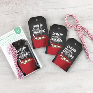 May include: A set of 12 gift tags with the text "Warm Winter Wishes" and a graphic of a red mug of hot cocoa. The tags are black with a white design and come with red and white twine for attaching. The tags are blank on the back.
