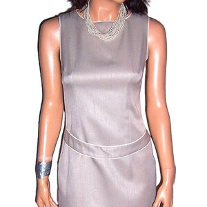 May include: A sleeveless, gray, fitted dress with a simple design and a subtle sheen. The dress has a straight skirt and a fitted bodice.