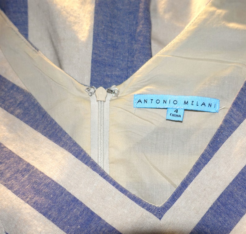 Może przedstawiać: Biało-niebieska sukienka w paski z zamkiem błyskawicznym i niebieską metką z napisem "ANTONIO MELANI" i "4 CHINA".