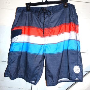 May include: Blue, red, and white striped swim trunks with a black drawstring and a Rip Curl logo on the side.
