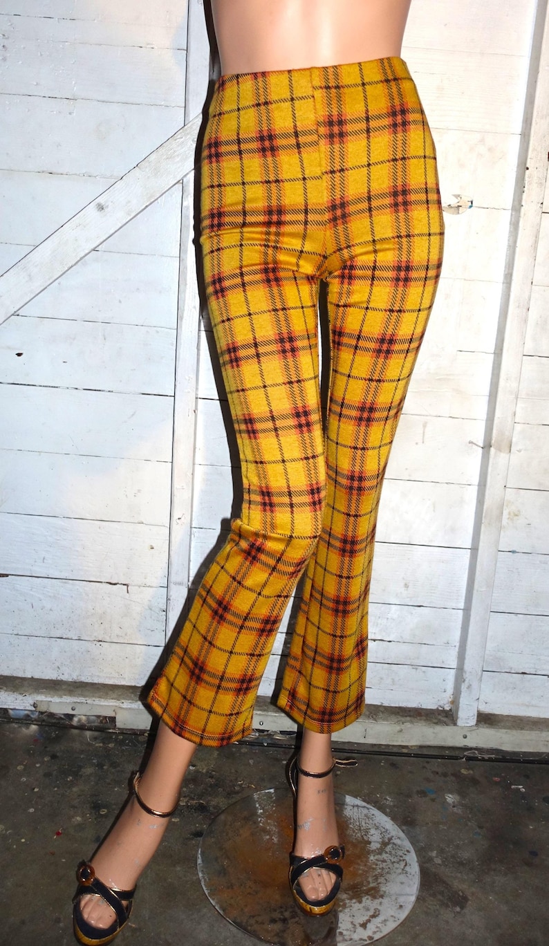 Puede incluir: Un pantal&oacute;n acampanado de cuadros amarillos y negros. El pantal&oacute;n est&aacute; hecho de una tela suave y el&aacute;stica y tiene una cintura alta.
