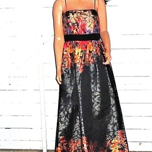 Puede incluir: Un vestido maxi negro con estampado floral. El vestido tiene un corpi&ntilde;o ajustado y una falda fluida. El estampado floral es en tonos de rojo, naranja, amarillo y morado.