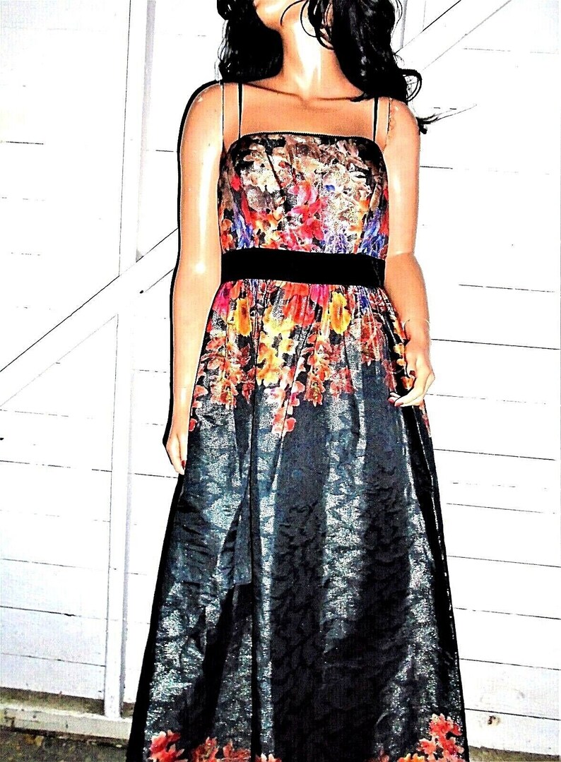 Puede incluir: Un vestido maxi negro con estampado floral y una cinta de terciopelo negro. El vestido tiene un corpi&ntilde;o ajustado y una falda fluida.