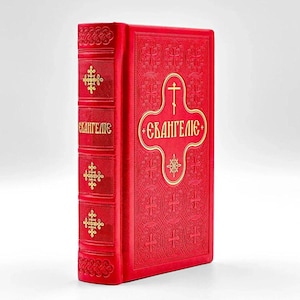 May include: A red book with gold embossed text and cross designs. The book's spine features gold cross patterns and the word "Евангелие". The cover has a gold cross and the same word in a decorative oval.