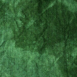 May include: Close-up of a textured, green fabric. The material has a woven appearance with visible fibers, creating a rough, uneven surface. The color is a deep, rich green, with variations in tone across the fabric.