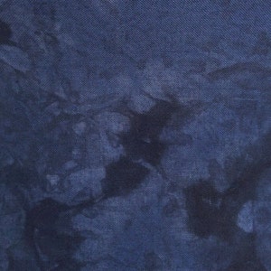 May include: A close-up of a dark blue fabric with a tie-dye pattern. The fabric has a textured, linen-like appearance.