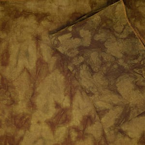 May include: Two pieces of fabric with a brown and green tie-dye pattern. The fabric is folded over itself, creating a layered effect.