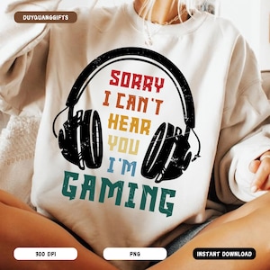 May include: A white sweatshirt with a graphic of a pair of headphones and the text "Sorry I can't hear you I'm gaming".