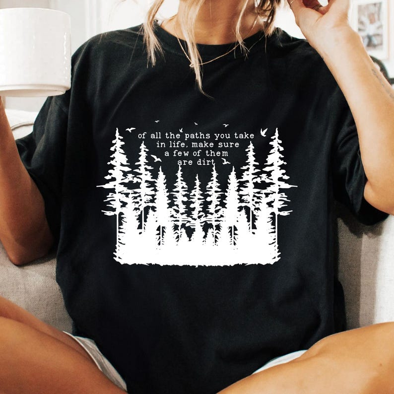 Puede incluir: Camiseta negra con un gr&aacute;fico blanco de un bosque y el texto "of all the paths you take in life, make sure a few of them are dirt".