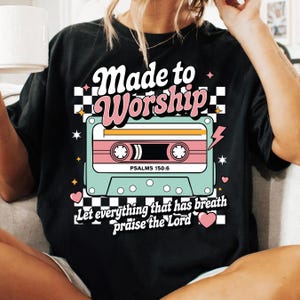 Pu&ograve; includere: Maglietta nera con un design a cassetta retr&ograve; e il testo "Made to Worship" e "Let everything that has breath praise the Lord". La cassetta ha il testo "Psalms 150:6" su di essa.