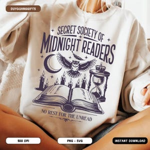 Op de afbeelding: Crèmekleurige sweatshirt met een grafisch ontwerp. Het ontwerp bevat de tekst "SECRET SOCIETY OF MIDNIGHT READERS", een uil, maan, kaarsen, een open boek en een zandloper. De zin "NO REST FOR THE UNREAD" is ook aanwezig.