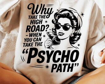 May include: Cream-colored sweatshirt with a black graphic of a woman wearing sunglasses and holding a cocktail. The text reads "Why take the high road? - When you can take the 'Psycho Path'" in a vintage font.