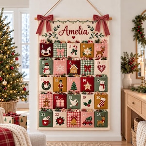 Pode incluir: Um calendário do advento de tecido para pendurar na parede com o nome Amelia impresso no topo. Possui vinte e cinco bolsos numerados, cada um decorado com bordados temáticos de natal como renas, bonecos de neve e presentes, suspenso por uma haste de madeira.