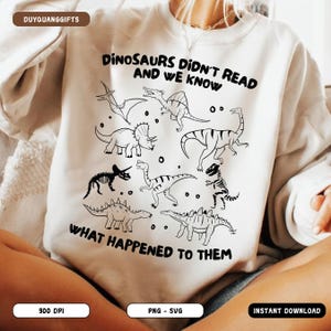 May include: Cream-colored sweatshirt featuring a black line drawing of various dinosaurs. The text "DINOSAURS DIDN'T READ AND WE KNOW WHAT HAPPENED TO THEM" is printed in black. The sweatshirt is a casual, comfortable style.