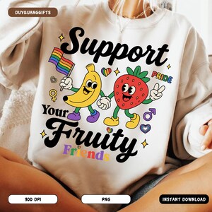 May include: White sweatshirt with the text "Support Your Fruity Friends" and a graphic of a banana holding a rainbow flag and a strawberry. The design includes hearts, stars, and gender symbols, promoting pride.