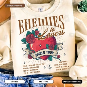 May include: A beige sweatshirt with a graphic design of a red heart with roses and a banner that says "Enemies to Lovers World Tour". The text "Featuring Feyre & Rhysand, Violet & Xaden, Jude & Cardan" is below the graphic. The dates "Feb 13 - Who Did This To You?, Feb 14 - Fated Mates, Feb 15 - Slow Burn, Feb 16 - Only One Bed" are listed below the graphic.