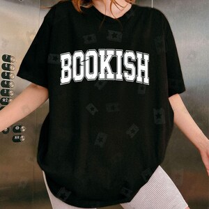 May include: Black oversized t-shirt with the word "BOOKISH" printed in white on the front. The shirt has a distressed, vintage look.