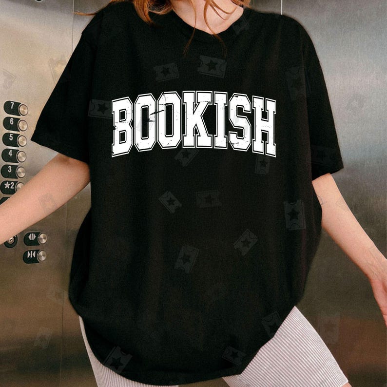 May include: Black oversized t-shirt with the word "BOOKISH" printed in white on the front. The shirt has a distressed, vintage look.