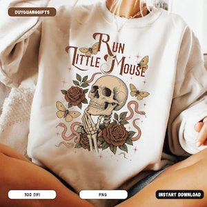May include: A white sweatshirt with a graphic design featuring a skull with a snake, roses, and butterflies. The text "Run Little Mouse" is printed on the sweatshirt.
