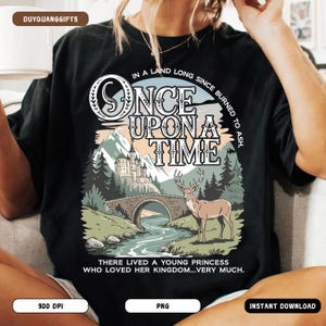 May include: Black t-shirt with a fairytale-themed graphic. The design features a castle, bridge, river, and a deer, with the words "Once Upon a Time" and the phrase "There lived a young princess who loved her kingdom...very much."