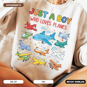 May include: White sweatshirt with a colorful graphic of various airplanes and the text "JUST A BOY WHO LOVES PLANES". The planes are in red, blue, green, yellow, and orange.