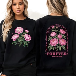 May include: Black sweatshirt featuring a floral design with pink peonies and green leaves. The front of the sweatshirt displays a bouquet of flowers. The back of the sweatshirt has the text "The Grass withers and the flower fades, but the word of God endures" and "FOREVER" with "ISAIAH 40:8".