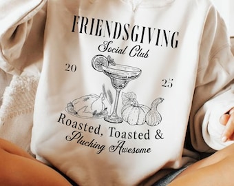 以下が含まれることがあります： カクテル、ローストターキー、カボチャ、そして「FRIENDSGIVING Social Club」の文字が描かれたグラフィックデザインのクリーム色のスウェットシャツ。デザインには数字の「20」と「25」、そして「Roasted, Toasted & Plucking Awesome」というフレーズも含まれています。