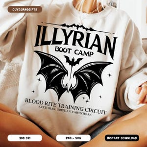 Peut inclure: Sweat-shirt crème avec un motif noir. Le motif comprend le texte "ILLYRIAN BOOT CAMP" au-dessus d'une chauve-souris et d'ailes de chauve-souris stylisées. En dessous, on peut lire "BLOOD RITE TRAINING CIRCUIT" avec du texte supplémentaire. Le sweat-shirt a un col rond.