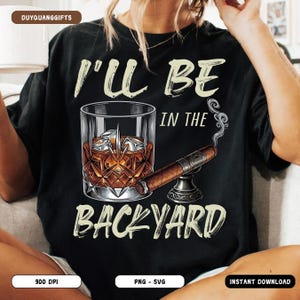 May include: Black t-shirt with the text "I'll Be In The Backyard". The graphic includes a whiskey glass with ice and a lit cigar on a stand. The shirt has a relaxed fit.