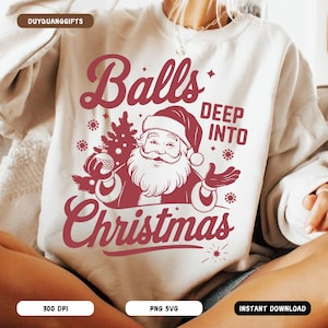 May include: A white sweatshirt with a burgundy graphic featuring Santa Claus, a Christmas tree, and the words "Balls Deep Into Christmas." The design includes snowflakes and a starburst.