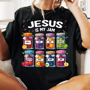 May include: Black t-shirt with the text "Jesus is my jam" and a graphic of jars filled with fruit. The jars are labeled with words like "faith", "love", "pray", "justice", "gratitude", "peace", "hope", and "joy".