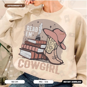 Peut inclure: Un sweat-shirt beige avec un motif graphique d'une pile de livres, un chapeau de cow-boy et des bottes de cow-boy. Le texte "Read 'Em Cowgirl" est imprimé sur le sweat-shirt.