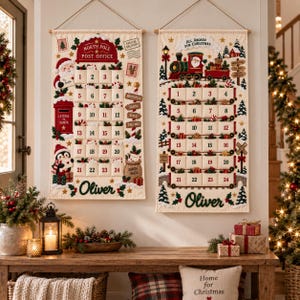 May include: Two rectangular fabric wall hangings featuring Christmas advent calendars with numbered pockets from 1 to 24. The left hanging depicts a North Pole Post Office with Santa and a penguin. The right hanging shows a train with Santa and the text All Aboard For Christmas. Both feature the name Oliver embroidered at the bottom.