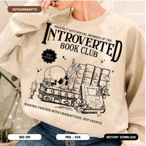 Puede incluir: Sudadera beige con un diseño gráfico negro que dice "Proudly Anti-Social Member of the Introverted Book Club" con una calavera y libros. El texto "Meet Weekly" está en un círculo sobre la calavera. El texto "Making Friends with Characters, Not People" está debajo de la calavera y los libros.