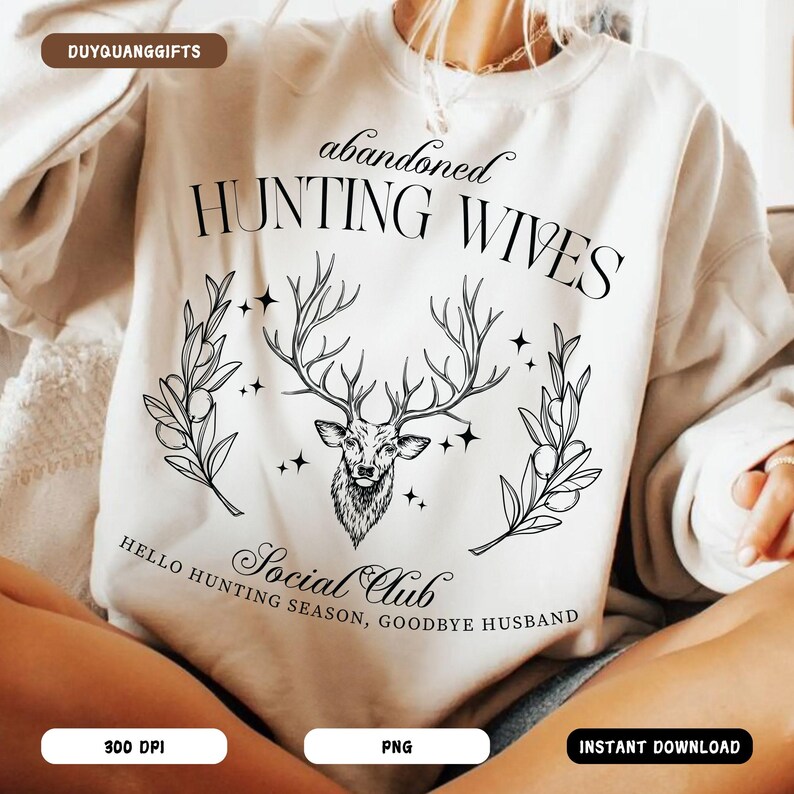 May include: A white sweatshirt with a black graphic design featuring a deer head with antlers, surrounded by leaves and stars. The text "abandoned hunting wives" and "Social Club" are also included in the design.
