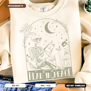 Peut inclure: Un sweat-shirt blanc avec un motif graphique d'un squelette lisant un livre dans une forêt éclairée par la lune. Le texte "Read in Peace" est sous le squelette.