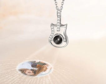 May include: Silver guitar-shaped necklace with a small black stone that projects an image when held up to a light source.