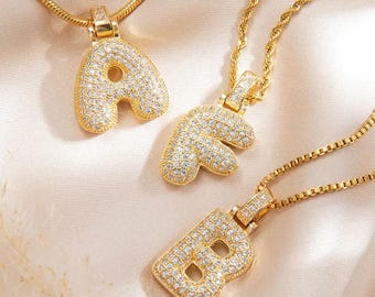 May include: Three gold necklaces with letter pendants. The pendants are made of gold and are covered in small, clear rhinestones. The letters are A, F, and B.