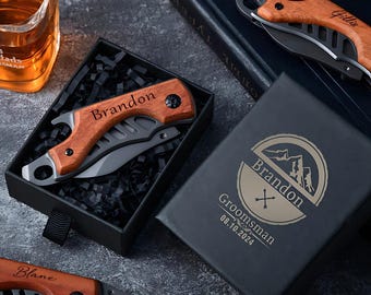 May include: A black gift box with a personalized engraved design featuring the name "Brandon" and the text "Groomsman 08.10.2024". The box contains a wooden handled pocket knife with a bottle opener.