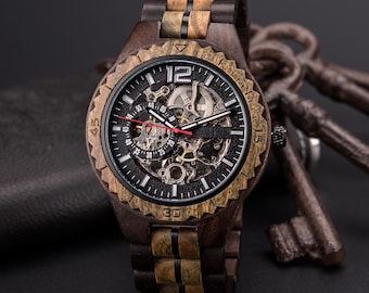 Puede incluir: Un reloj de pulsera de madera con una correa de madera marrón oscuro y una esfera negra. La esfera del reloj tiene un diseño de esqueleto, que revela el mecanismo interno. El reloj tiene un bisel de madera marrón y un segundero rojo.