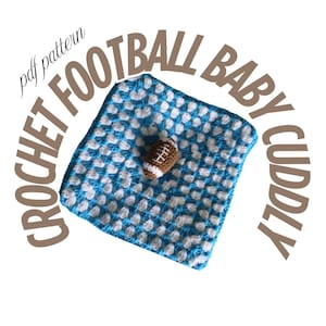 May include: A crocheted baby cuddly blanket with a football design. The blanket is square, with a blue and white pattern, and a small brown and white football in the center. Text reads "CROCHET FOOTBALL BABY CUDDLY pdf pattern".