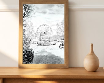 Può includere: Uno schizzo in bianco e nero di una scena di parco con una grande ruota al centro, un muro di pietra e una panchina. La scena è incorniciata in una cornice di legno marrone chiaro.