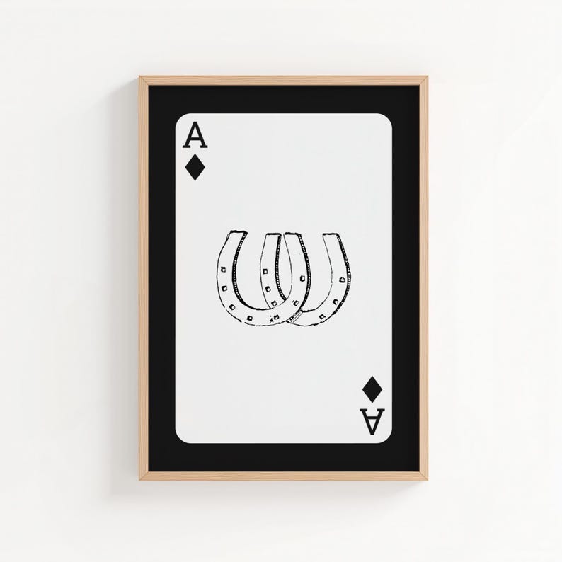 May include: A framed print of the Ace of Diamonds playing card. The card features a white background with a black border and a black diamond at the top and bottom. Three black horseshoes are in the center of the card.