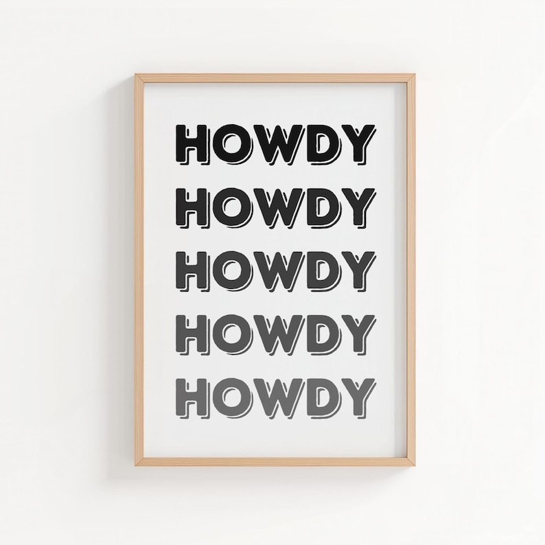May include: A framed print with the word "HOWDY" repeated five times in a bold, black font. The text is centered on a white background, and the frame is a light wood color. The artwork is a simple, yet eye-catching piece.