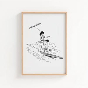 May include: Black and white illustration of two people surfing. One person is standing on a surfboard, while the other is in the water. The text "surf's up cowboy" is written above the figures.