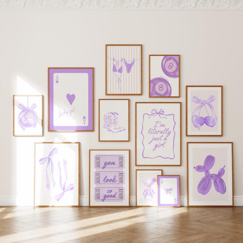 May include: A gallery wall set of eleven framed prints featuring purple illustrations including a disco ball, an ace of hearts card, a bikini, eight balls, cowboy boots, a bow, ticket stubs with text, and a balloon dog with the text I'm literally just a girl.