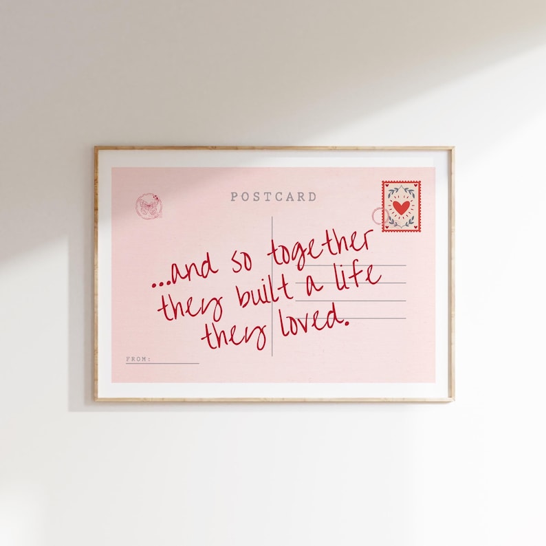 Puede incluir: Una impresi&oacute;n rectangular enmarcada con un dise&ntilde;o de postal rosa claro. El texto dice: "...and so together they built a life they loved." Incluye un sello de coraz&oacute;n rojo, un matasellos circular y la palabra "POSTCARD" en letras de color gris oscuro.