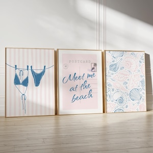 May include: Three framed art prints with a beach theme. One print shows a blue bikini hanging on a clothesline against a pink striped background. Another says "Meet me at the beach" on a pink background. The third print has a seashell pattern.